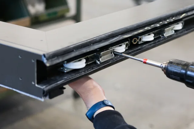 Close-up of a worker using a drill to assemble metal components indoors. Modular vs custom exhibition stands: which is right for your UK trade show?