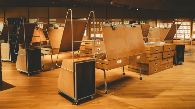 Interior view of a modern art gallery with wooden exhibition stands and artwork displays. Trade show exhibiting in England: six health and safety laws behind an exhibitor's stand